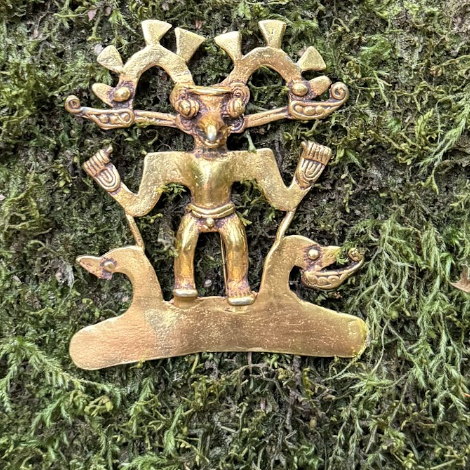 A gold Bird Man pendant, Veraguas–Gran Chiriquí / Diquís tradition, photographed on moss