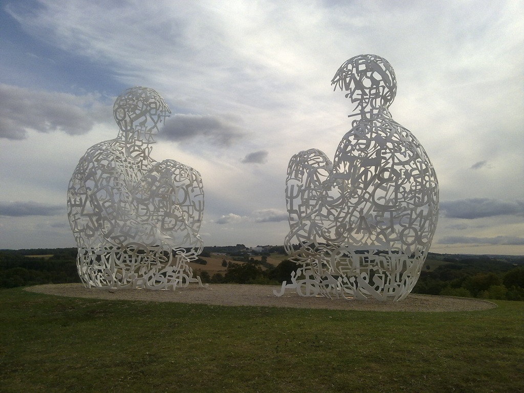 Two seated figures made of letters, facing each other on a hill