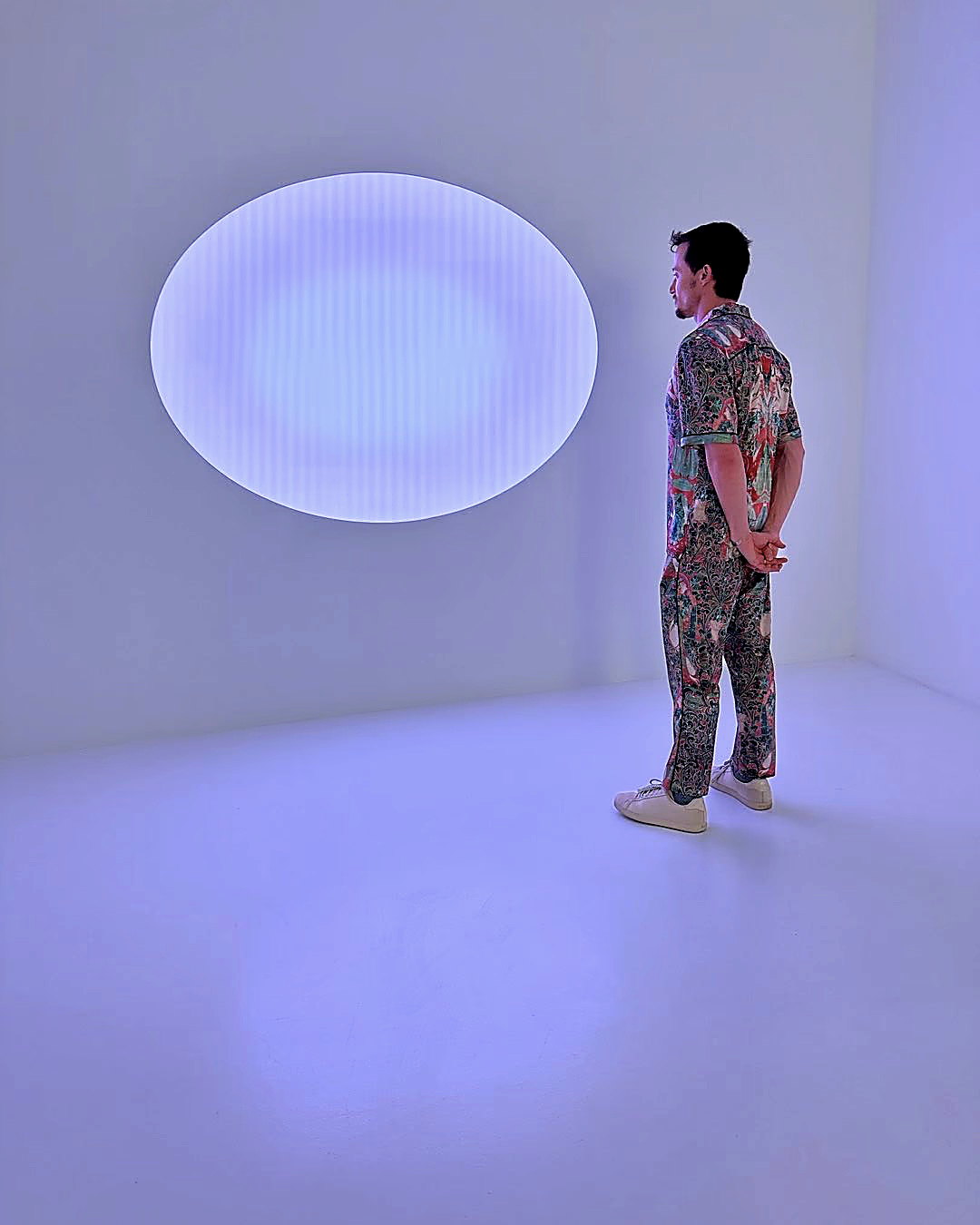 John Wolf standing before a James Turrell light oval